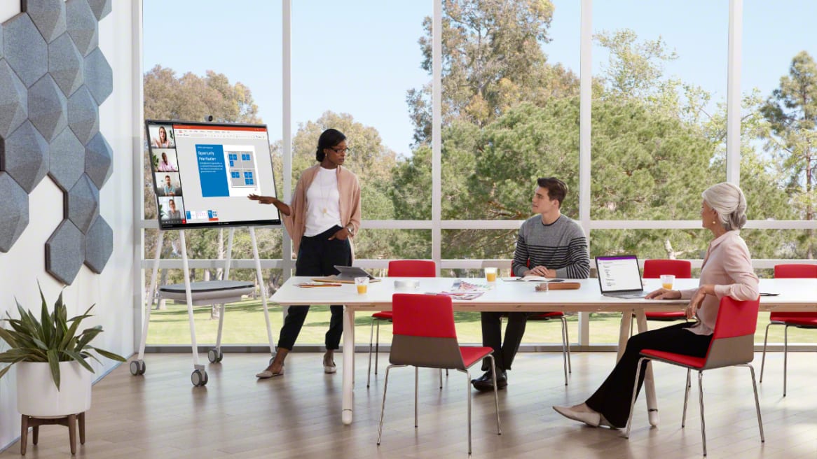 Woman makes a presentation using a Steelcase Roam Mobile Cart during a meeting in a room with a Potrero415 table and Montara650 chairs